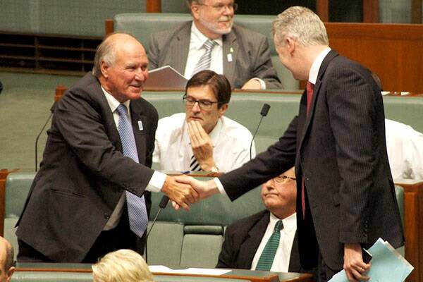 Tony Windsor shakes hands with Tony Burke in Parliament.